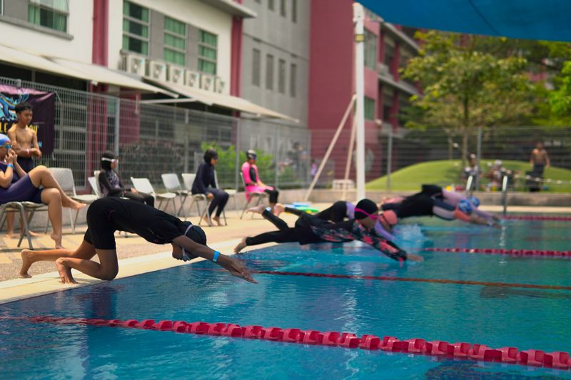 Swimmers diving in from the pool edge at the start of a race
