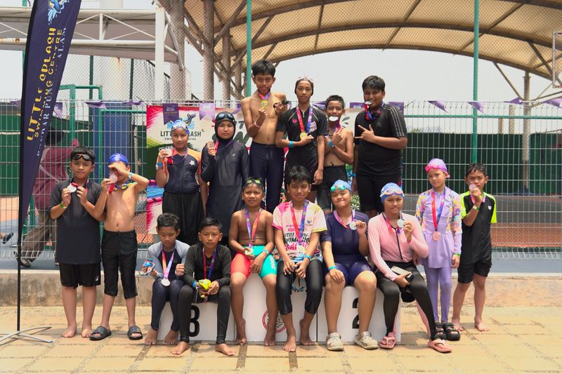 A larger group of swimmers showing their medals around the podium