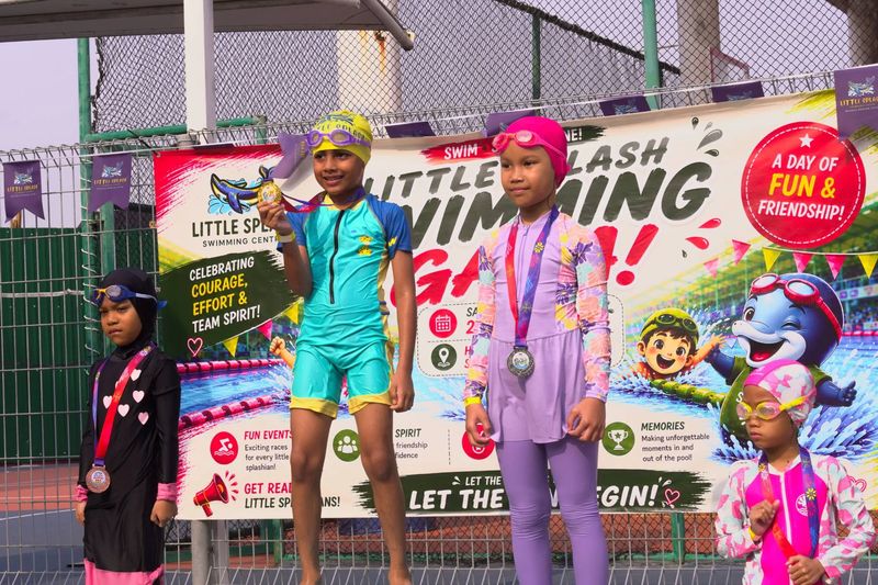 Medal winners standing on the podium in front of the Swimming Gala banner