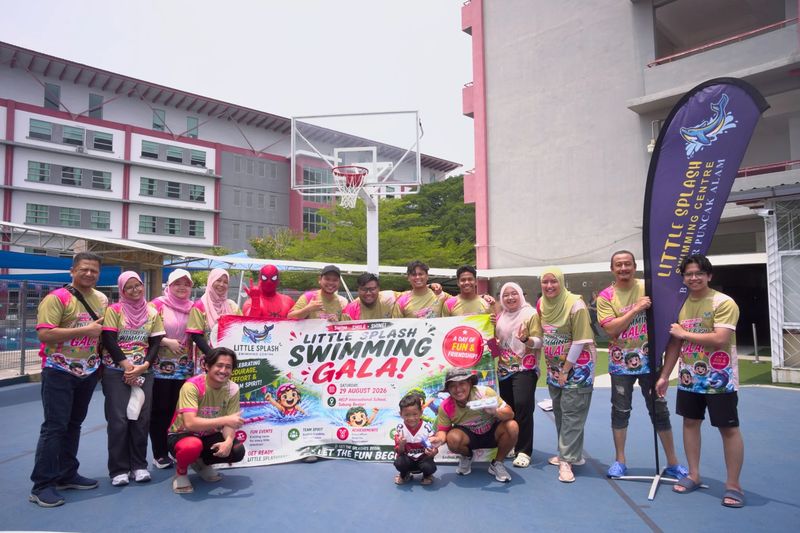 The Little Splash coaches and crew, with a costumed Spider-Man, holding the Swimming Gala banner